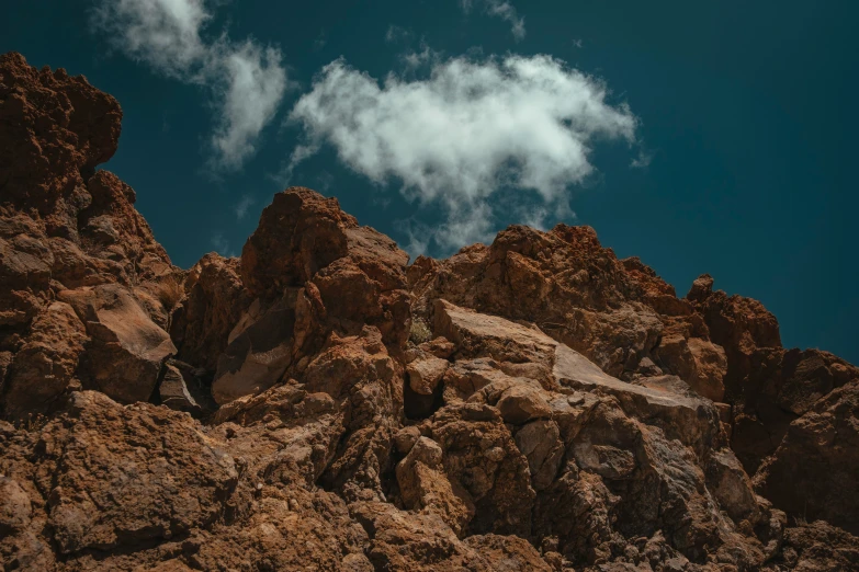 rocks are piled against the mountain with a small cloud