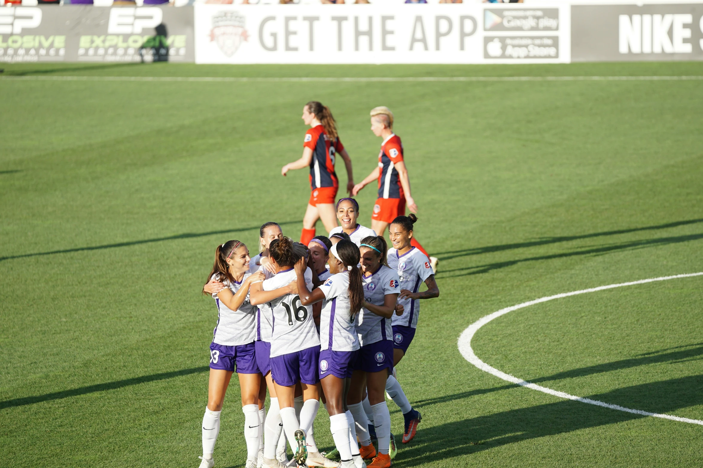 women's soccer team huddled around the head coach at a soccer game