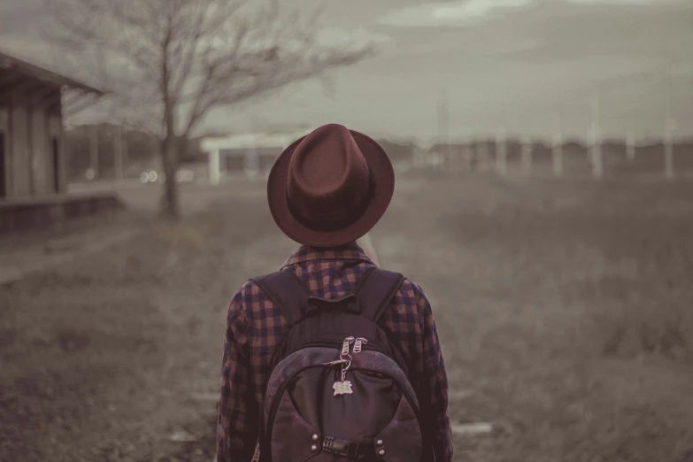 a man with a hat walks away down the road