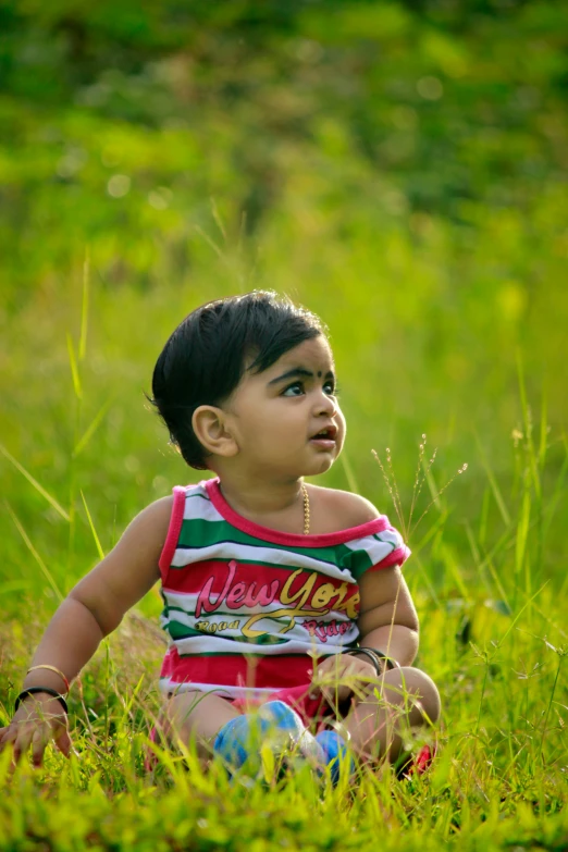 an adorable little boy sits in the grass