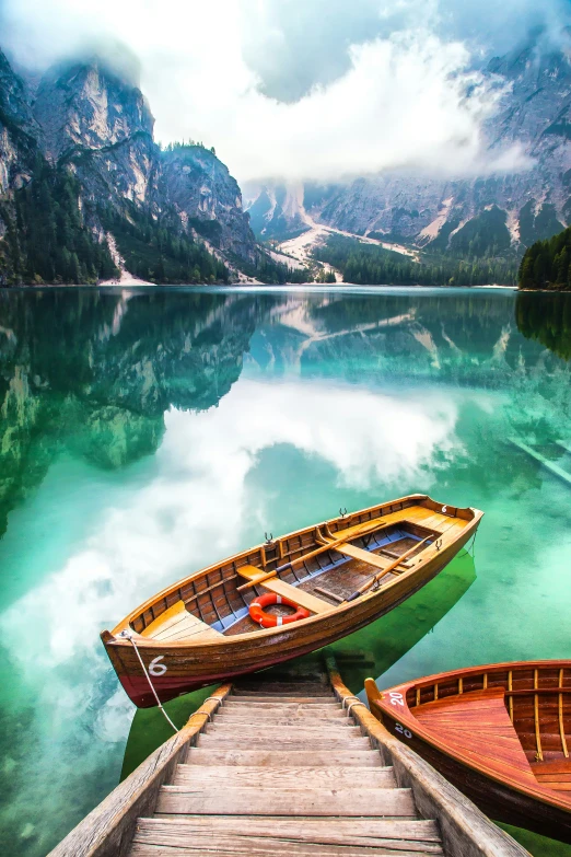 two wooden boats parked on a dock by the water