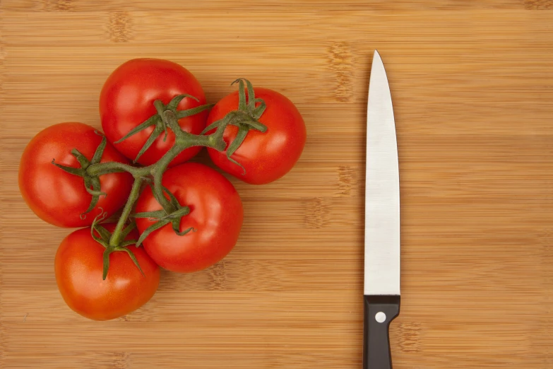 tomatoes on a  board next to a knife