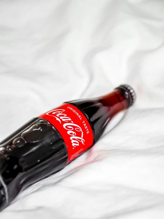 a close - up s of a coca cola bottle on a bed