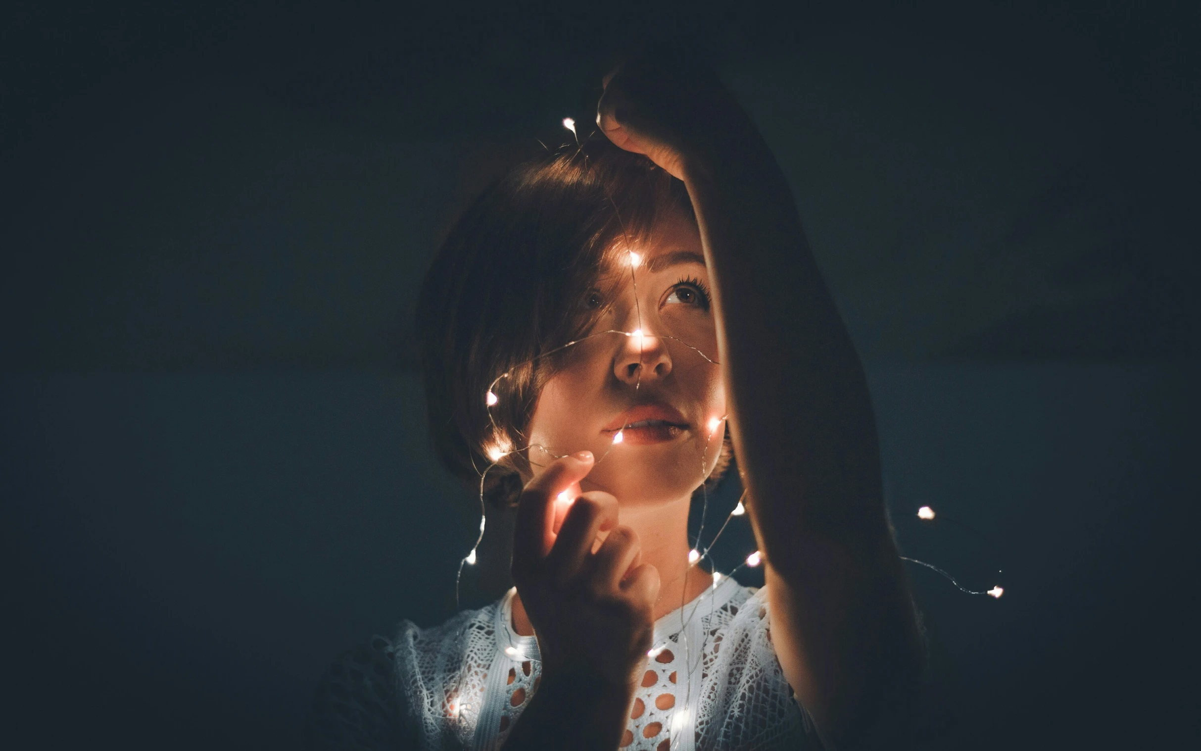 a person standing in the dark with their hands over their head