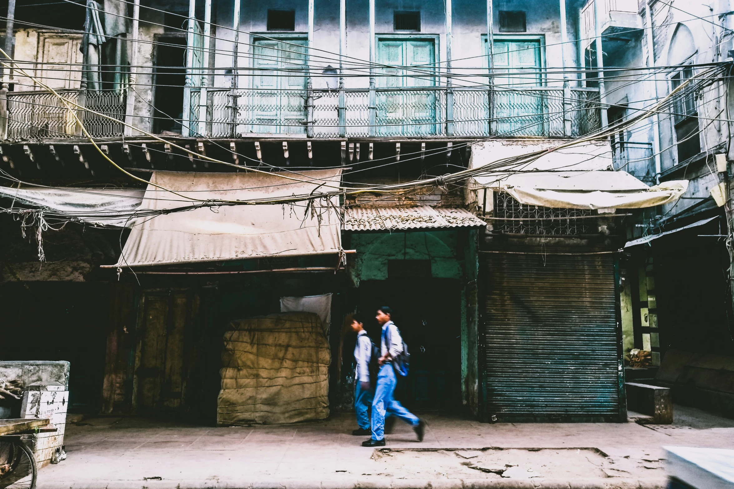 two men walking outside an old building in the middle of a slum area