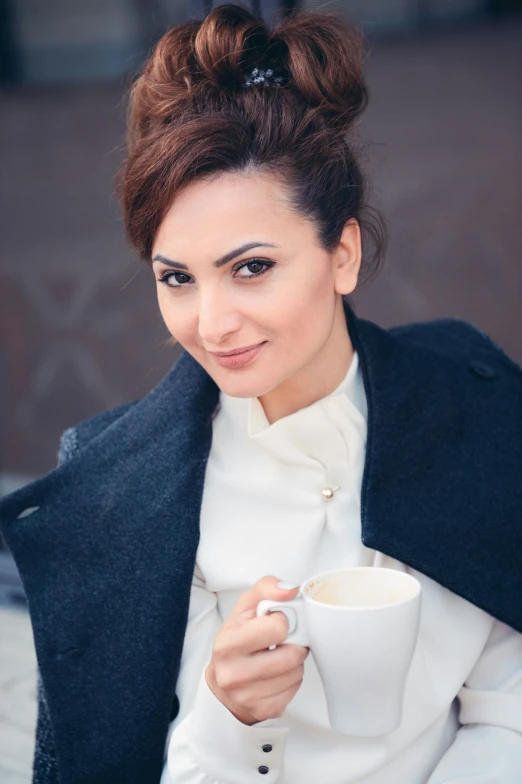 woman sitting down with a cup and jacket on