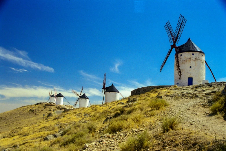 several windmills on top of a hill with blue sky