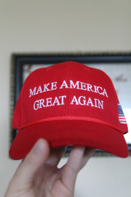 a hand holding a red make america great again hat