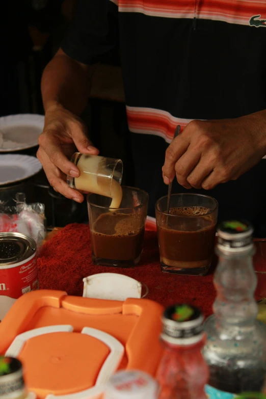 the person is adding chocolate to glasses on the table