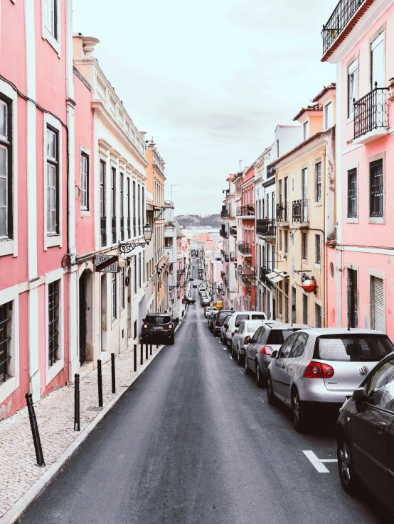 many cars are parked along a long empty street