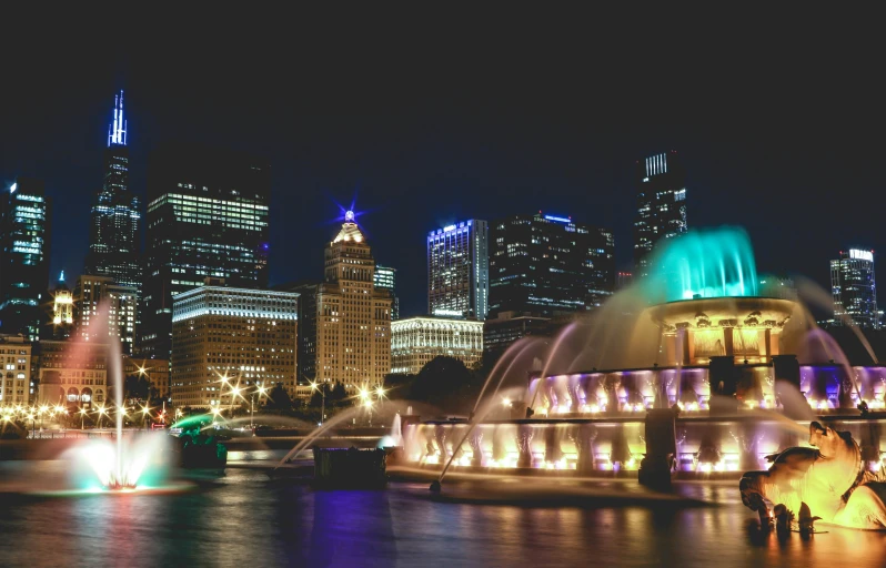 night scene of water fountain in front of the city