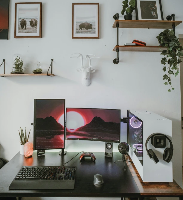 a desk with a keyboard, monitor and headphones on it