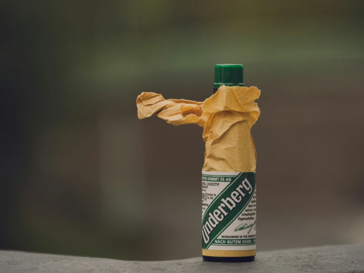 a wrapped up bottle sitting on top of a cement slab