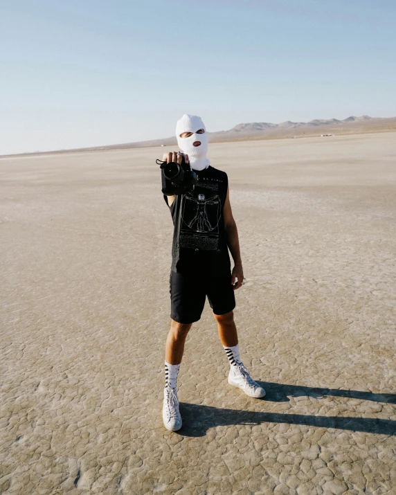 a man in a black shirt and white mask holding up a white ball