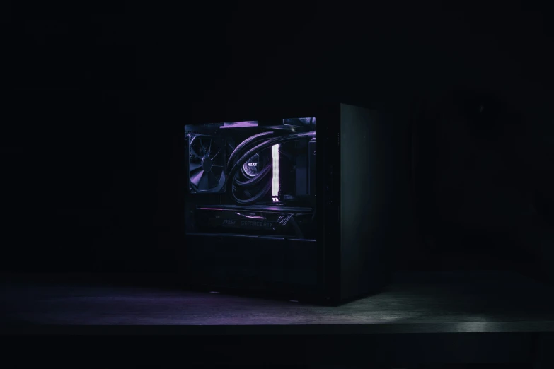 a computer case sitting in the dark with purple light coming from it