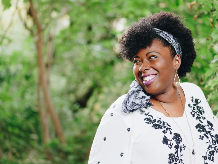 woman in white shirt with hair wrapped around neck smiling