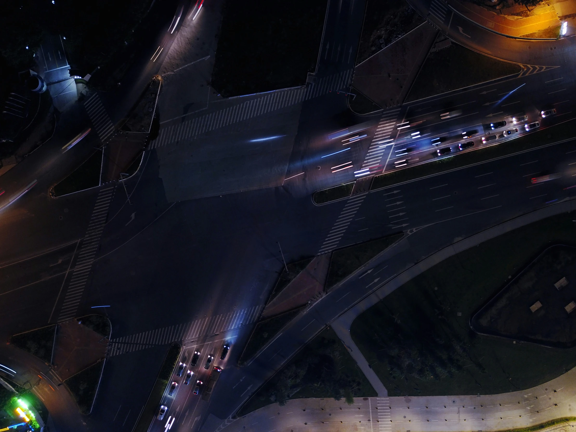 a night view shows overhead road lights, with a bus on a busy road