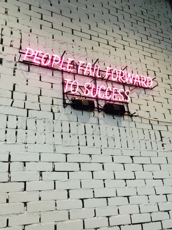 a neon sign attached to the side of a brick wall