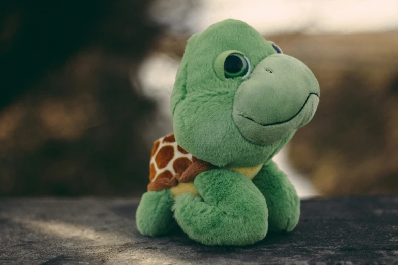 a green stuffed animal turtle with a brown bow on its neck