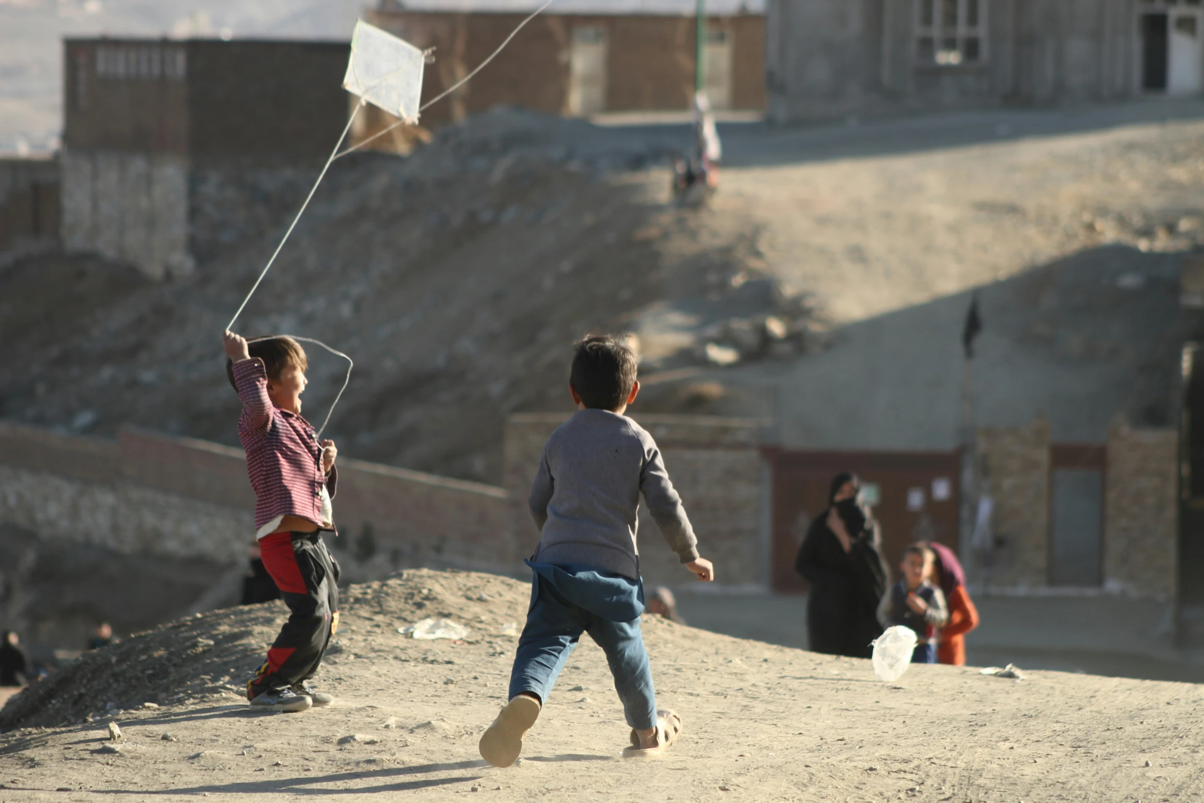 two young children playing with a kite in the wind