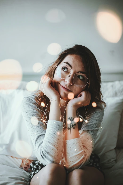 a woman is sitting on a bed with a light on her face