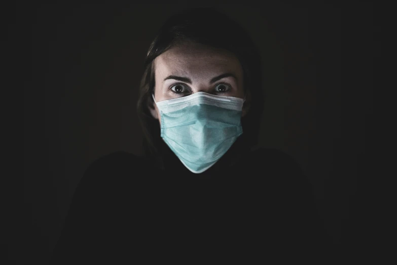 a woman wearing a blue face mask in the dark