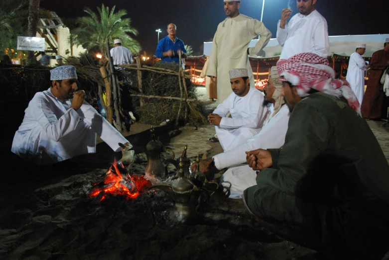 some men are sitting around a campfire