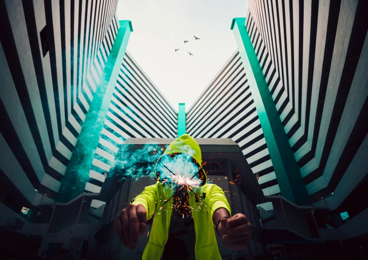 a person in neon green stands underneath tall buildings