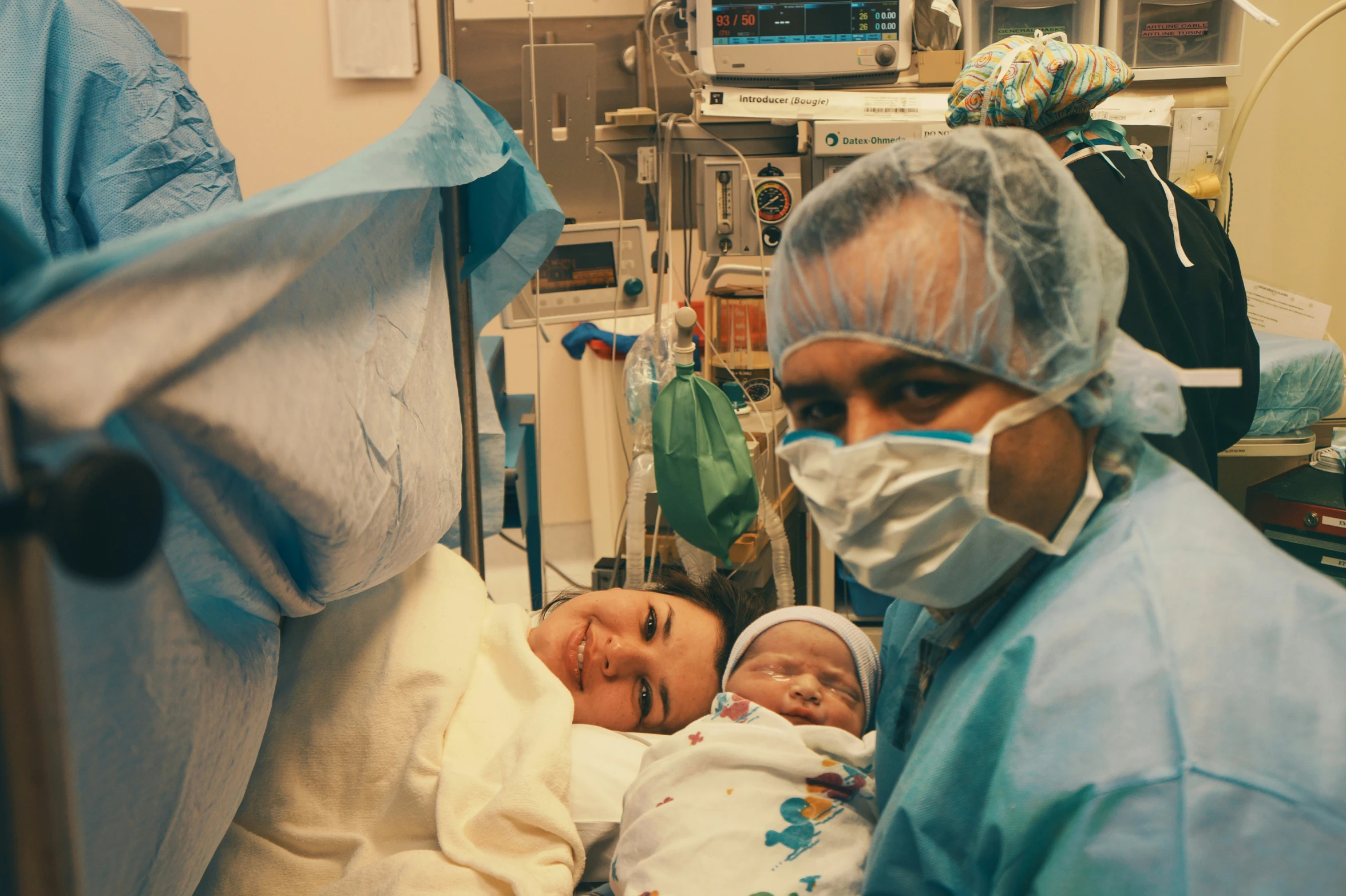 a hospital worker holding a baby and wearing a face mask