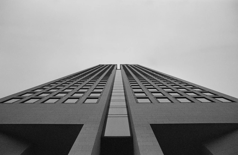 a tall building with several windows that has a plane flying in the sky