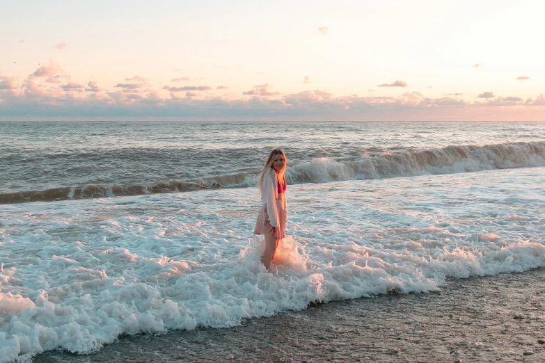 a woman is standing in the surf near the shore