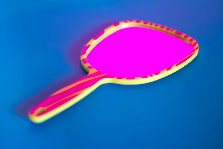 a pink paddle on blue surface with yellow highlights