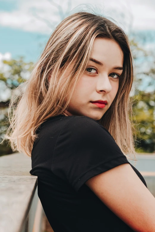 a girl with long hair leaning against a railing