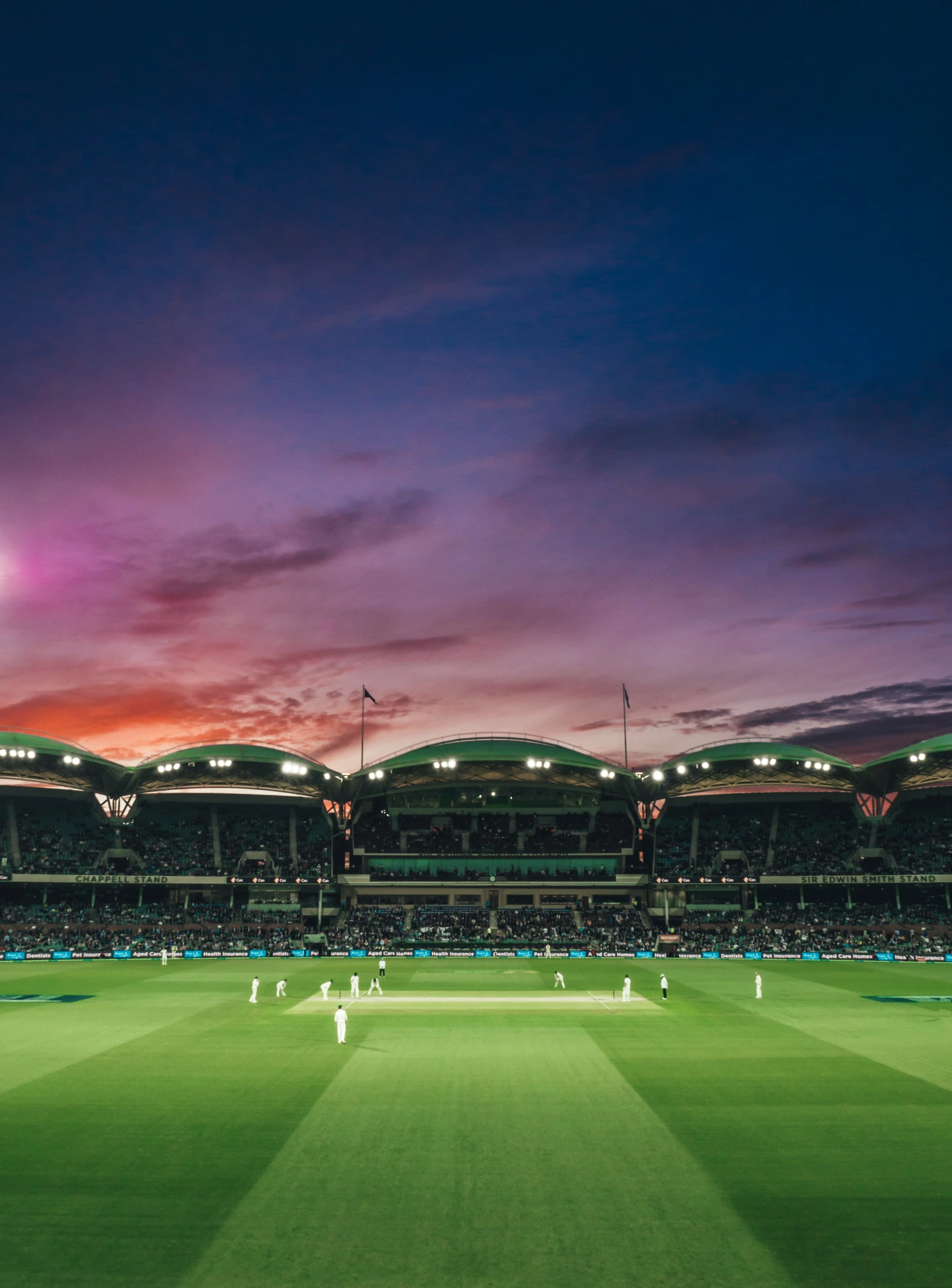 a stadium with people playing a game of cricket