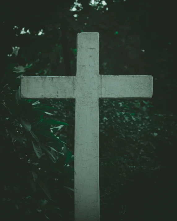 a white cross sitting on top of a grass covered field