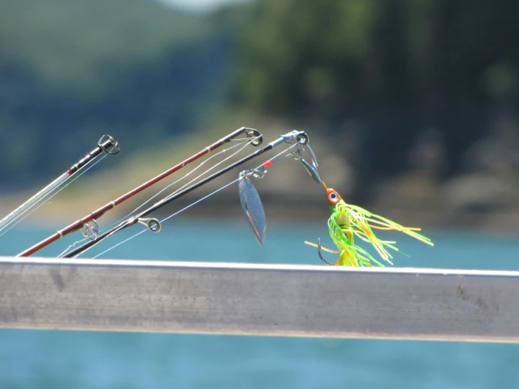 two fishing rods, fishing gear and one fish hook are on the edge of a boat