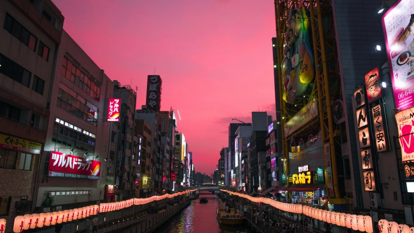 a river is surrounded by tall buildings under pink sky