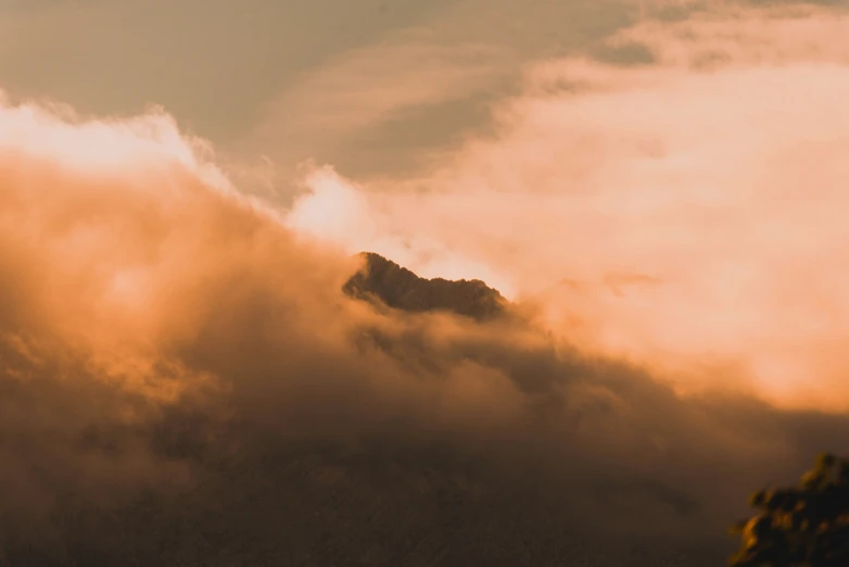 clouds cover the top of a mountain and trees