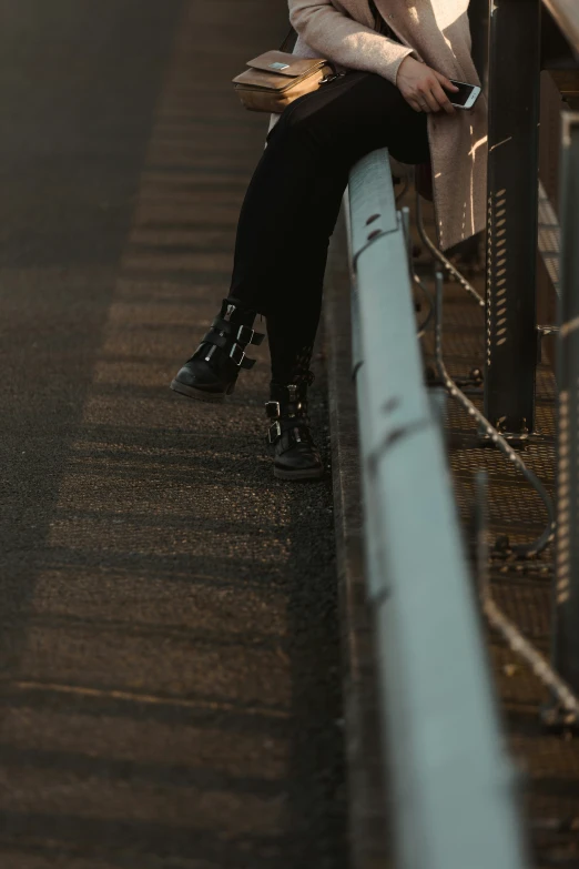 a woman sitting by a fence holding a bag with her right hand