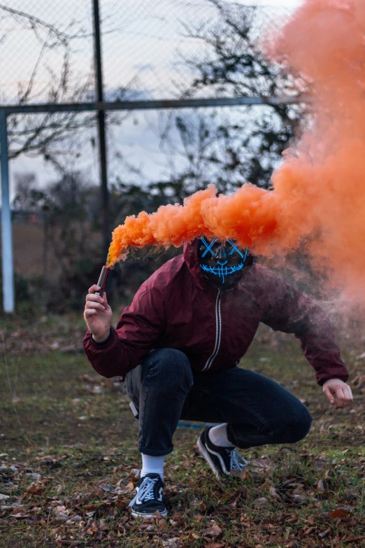 a man with orange smoke and a mask on kneeling down