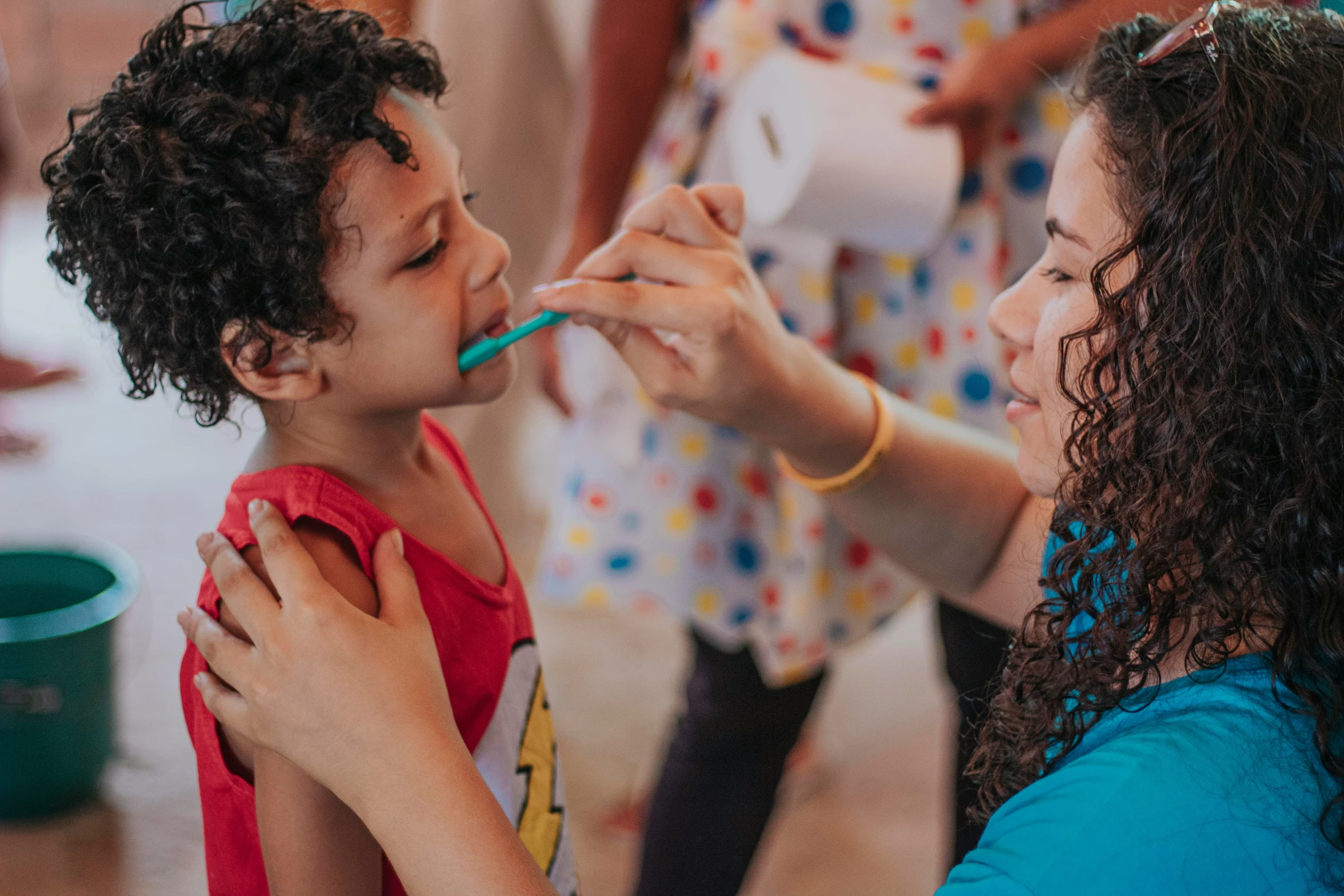 a woman putting a toothbrush in a little boy's mouth