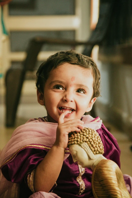 a smiling young indian girl is dressed in a purple cloth