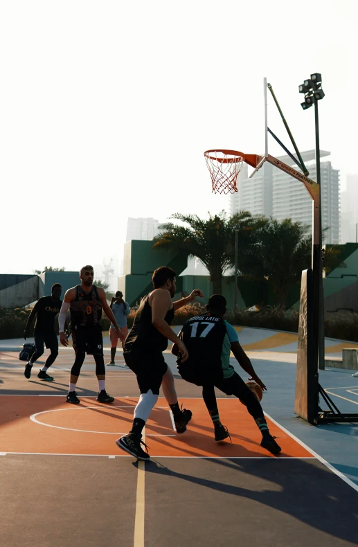 people playing basketball on an outdoor court with lots of lights