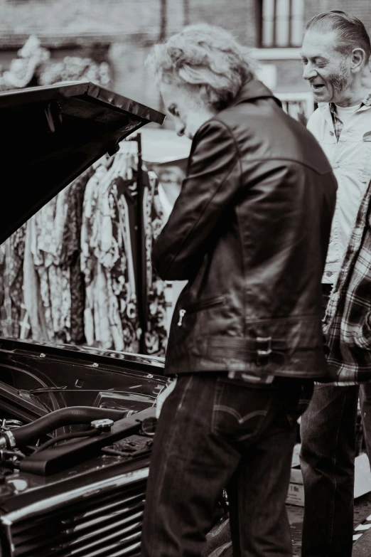 two people standing next to each other by a car