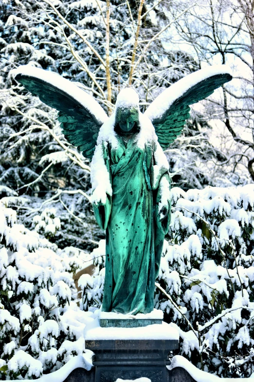 a angel statue stands in the snow among trees