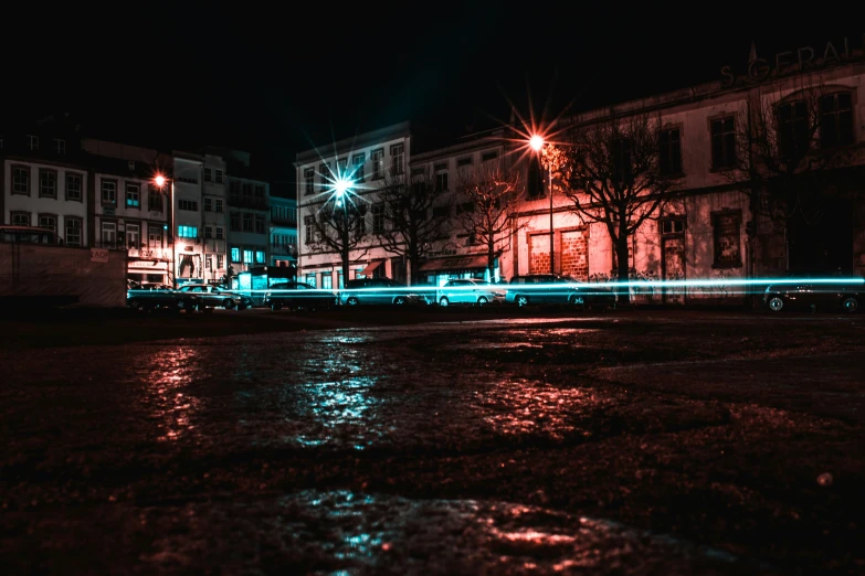lights are reflecting off the wet ground on a street