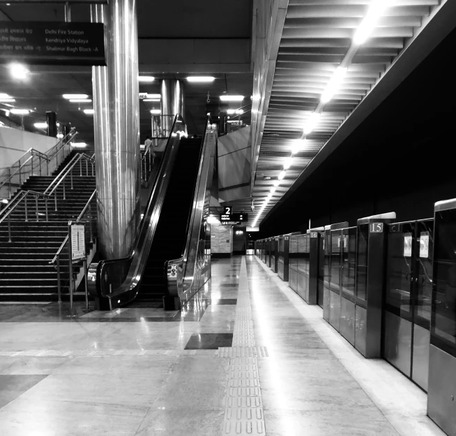 an escalator leading to a loading area with benches and stairs