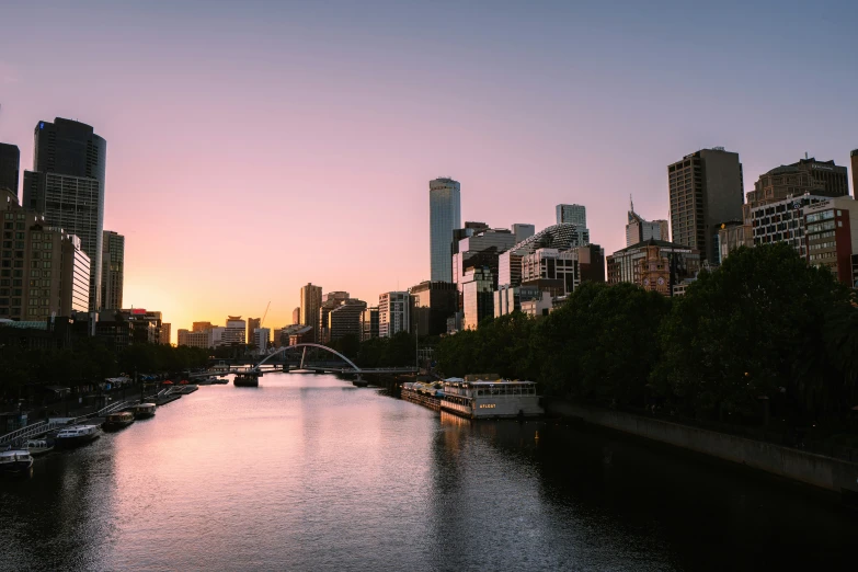 the sun rises over a river running through a large city