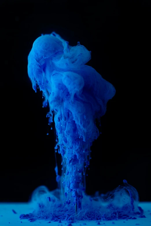 a bright blue substance floating in a black background