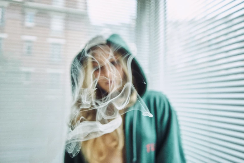 a woman in a green hoodie looks out the window